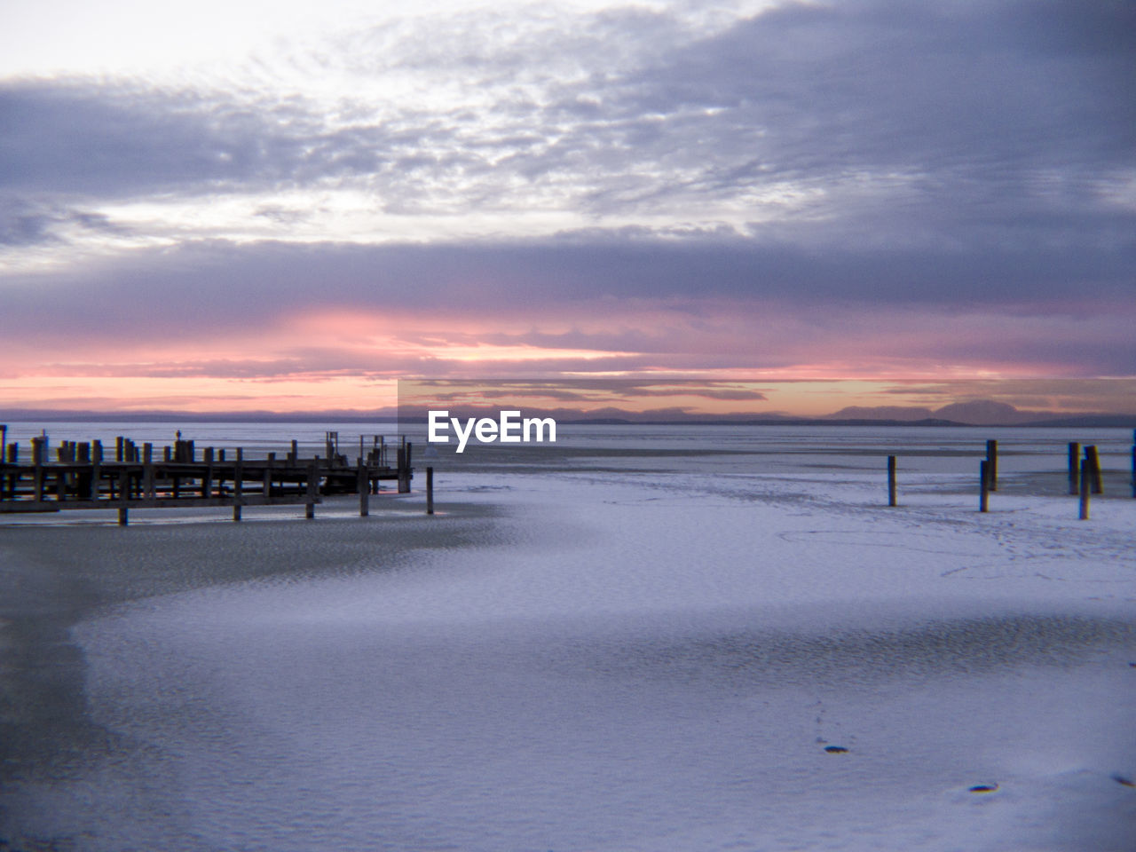 Scenic view of beach against sky at sunset