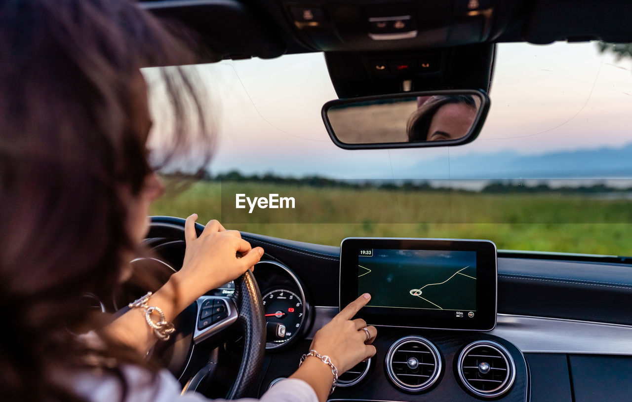 Young girl driving car using navigation system on electronic dashboard building route to destination 