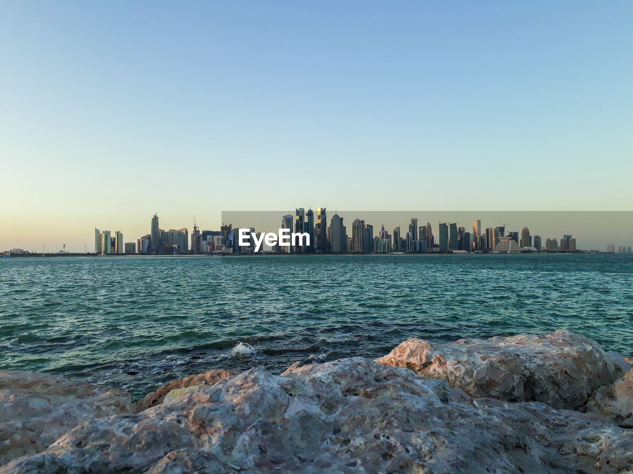 Scenic view of sea and buildings against clear sky