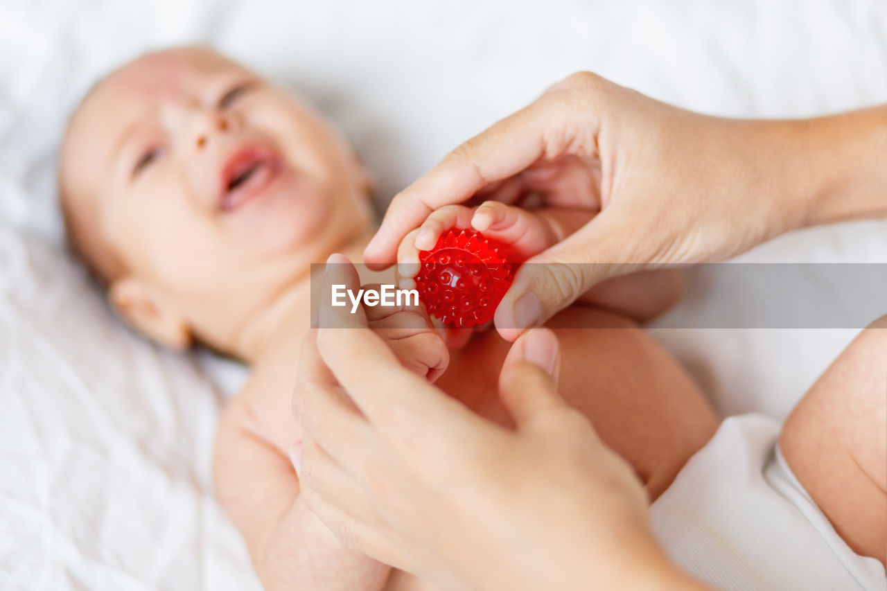 Mother holds newborn baby's palm hands. tiny fingers in woman's hand. cozy morning at home.