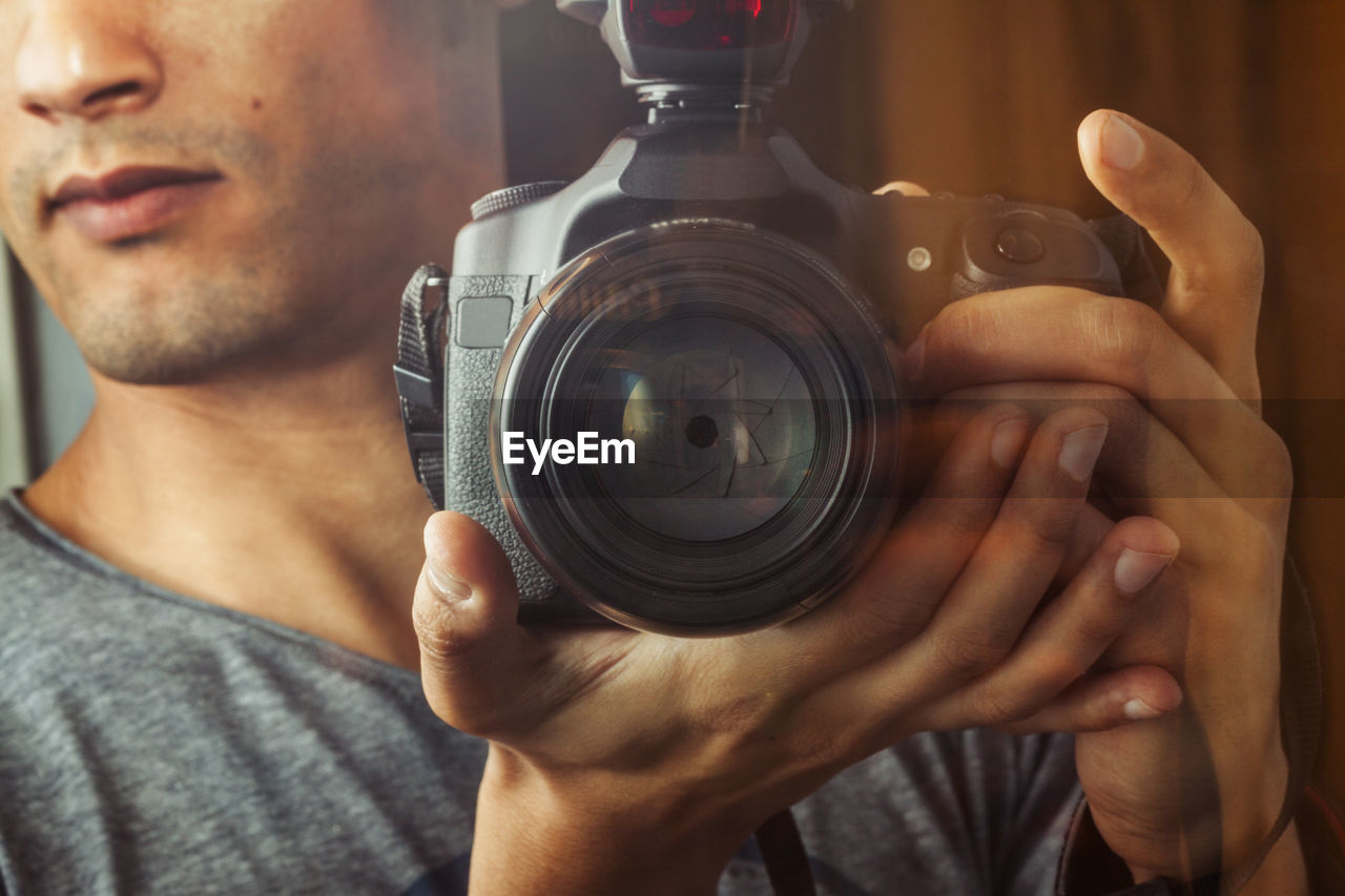 Midsection of teenage boy photographing with camera