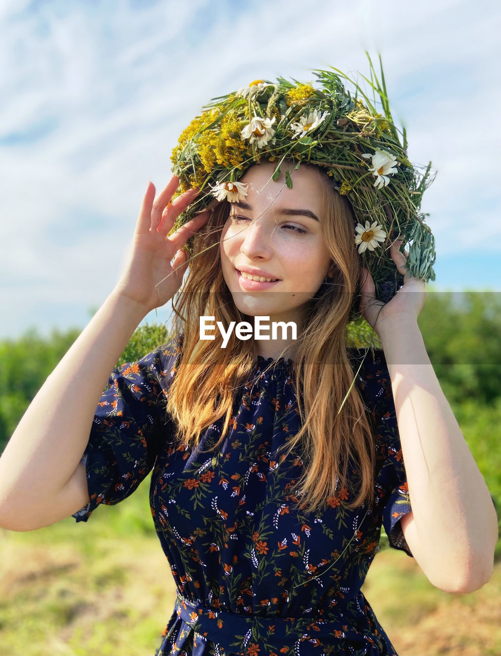 portrait of smiling young woman standing against trees