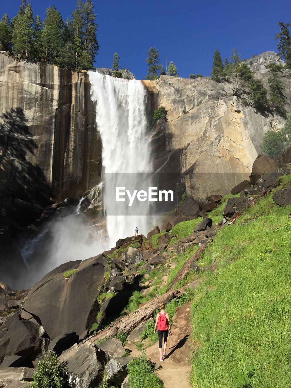 Rear view of woman walking towards waterfall