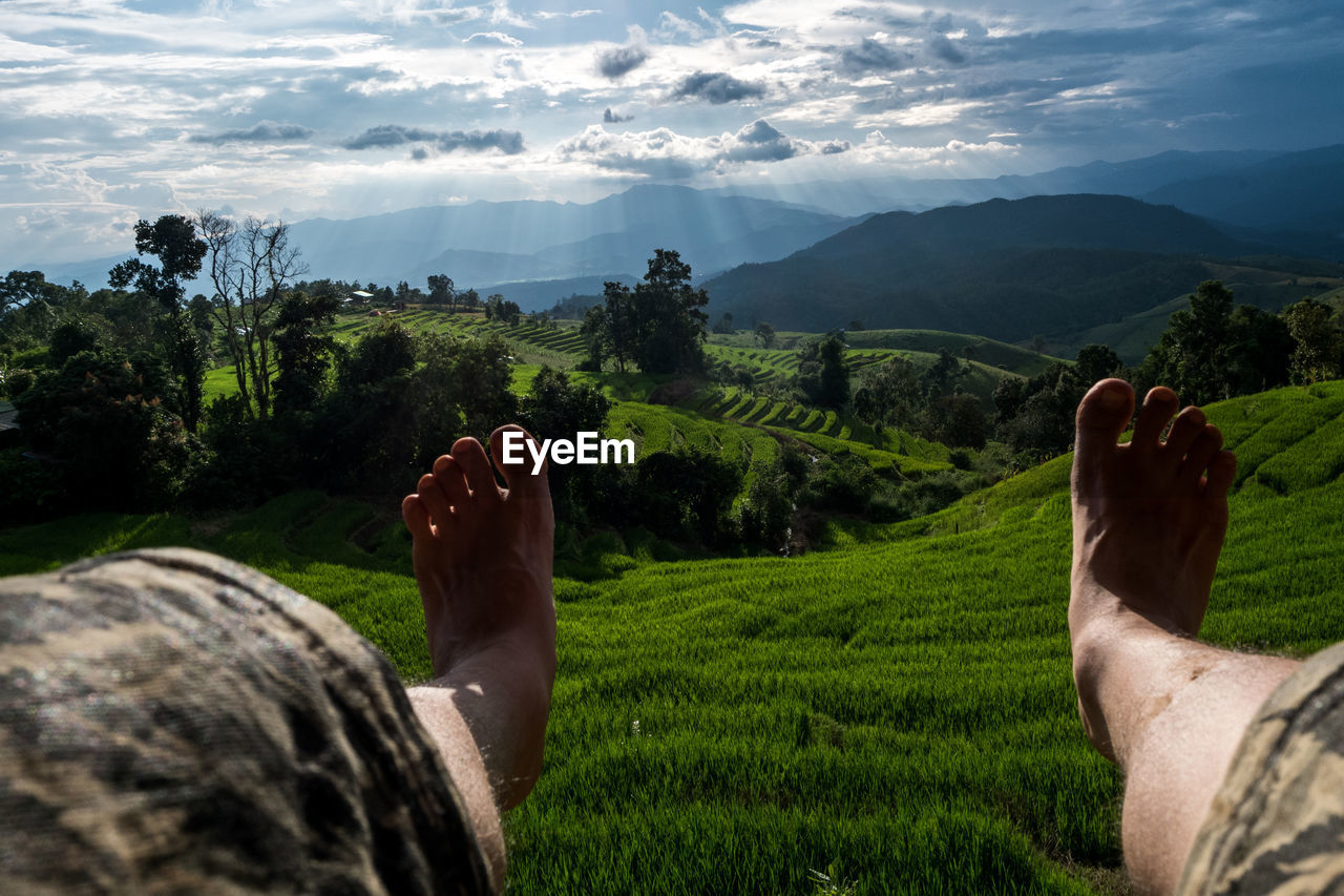 Low section of man on land against sky