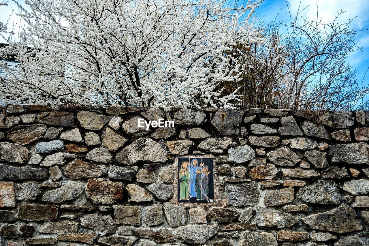 Religious picture frame on stone wall against trees