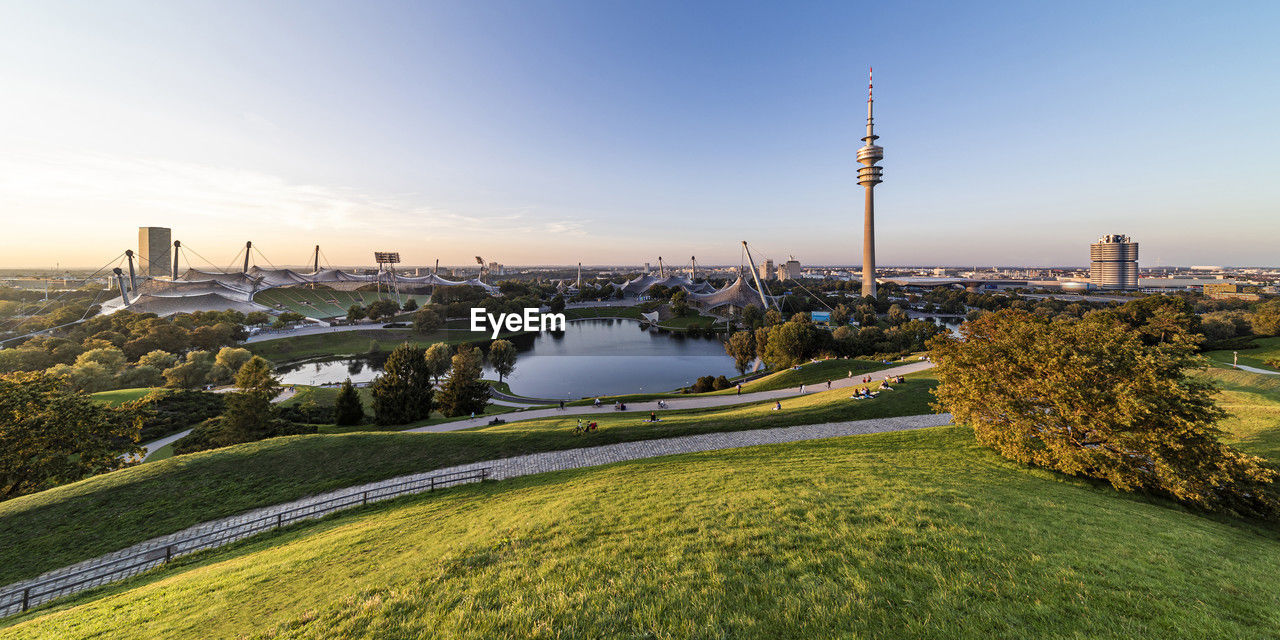 Germany, bavaria, munich, panoramic view of olympic park with olympic tower, bmw building and pond in background