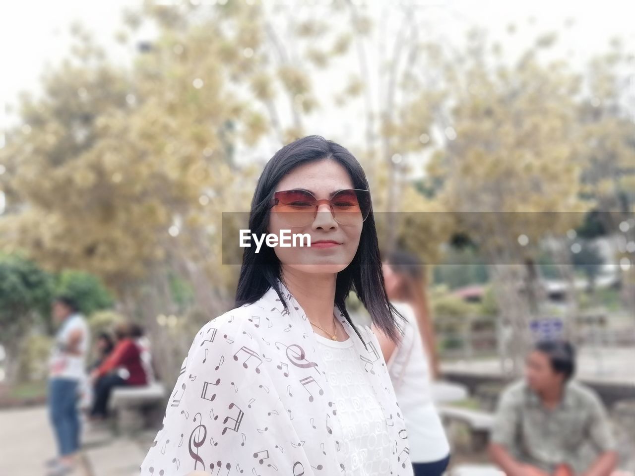 Portrait of woman wearing sunglasses against trees