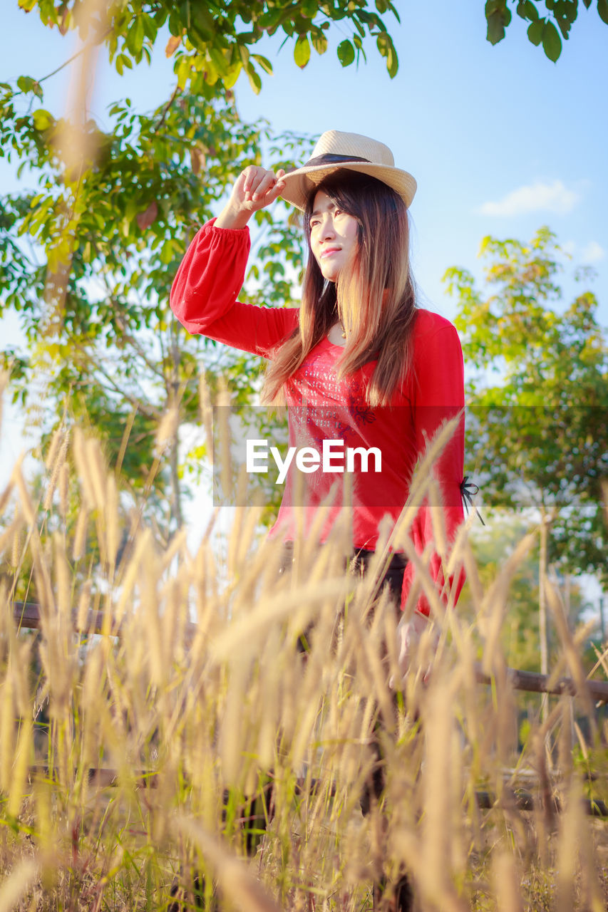 YOUNG WOMAN STANDING IN FIELD