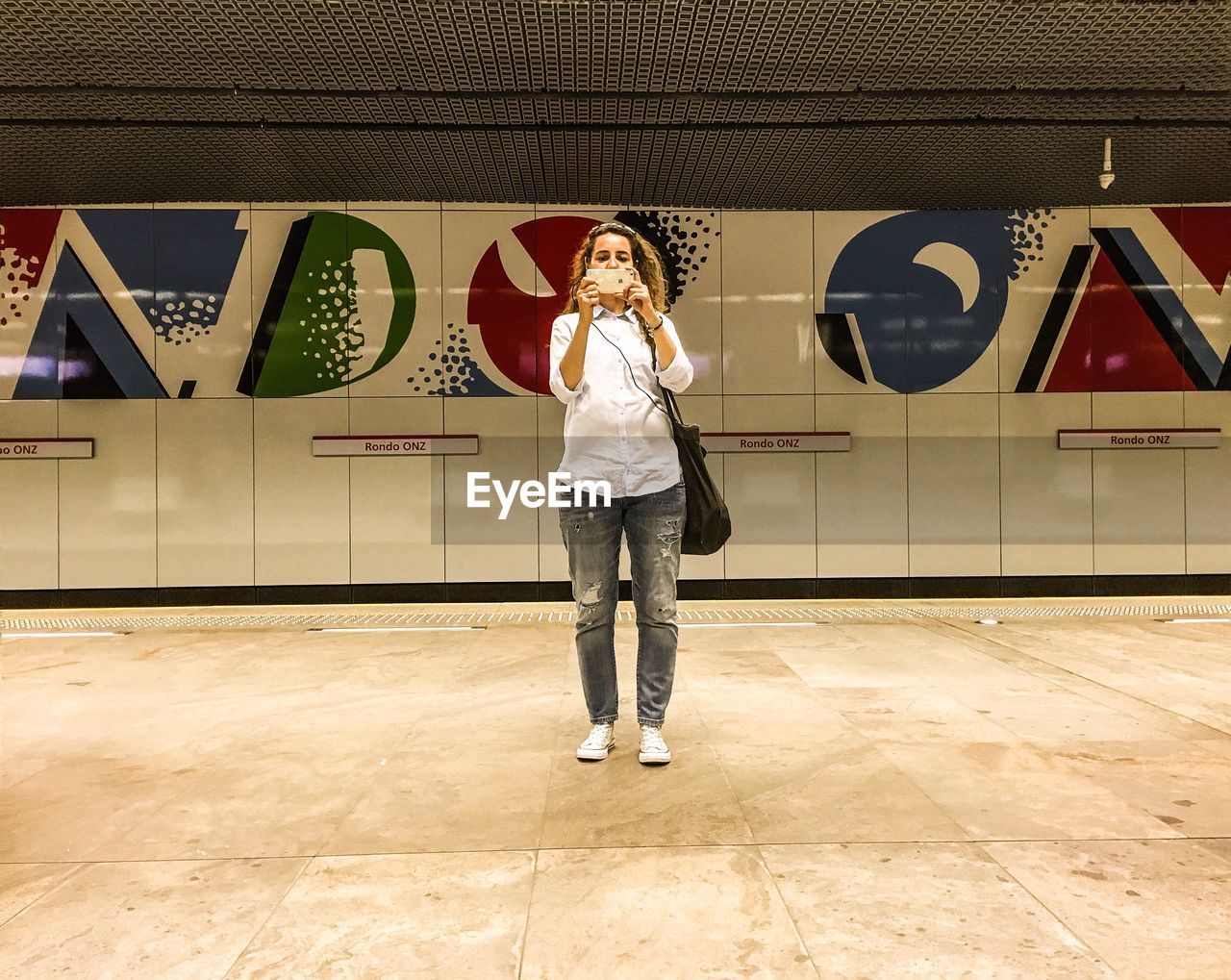 Young woman photographing in subway station