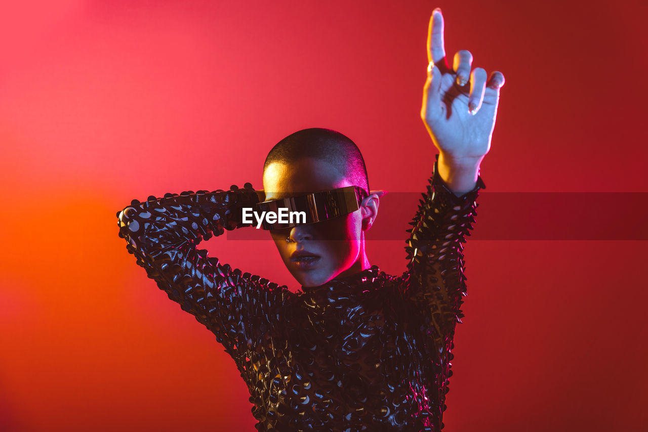 Woman wearing eyeglasses standing against red background