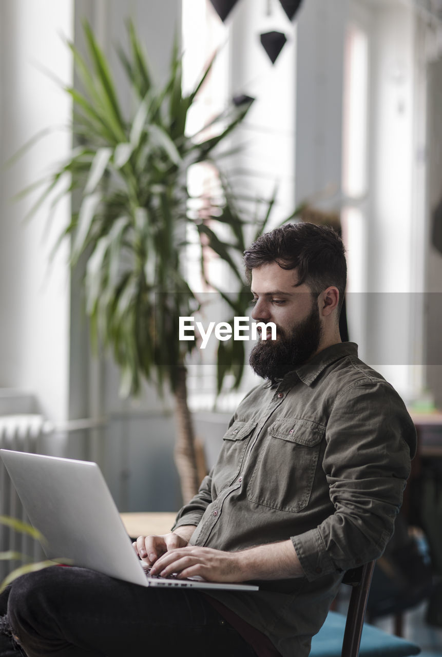 Young man using laptop while sitting on chair