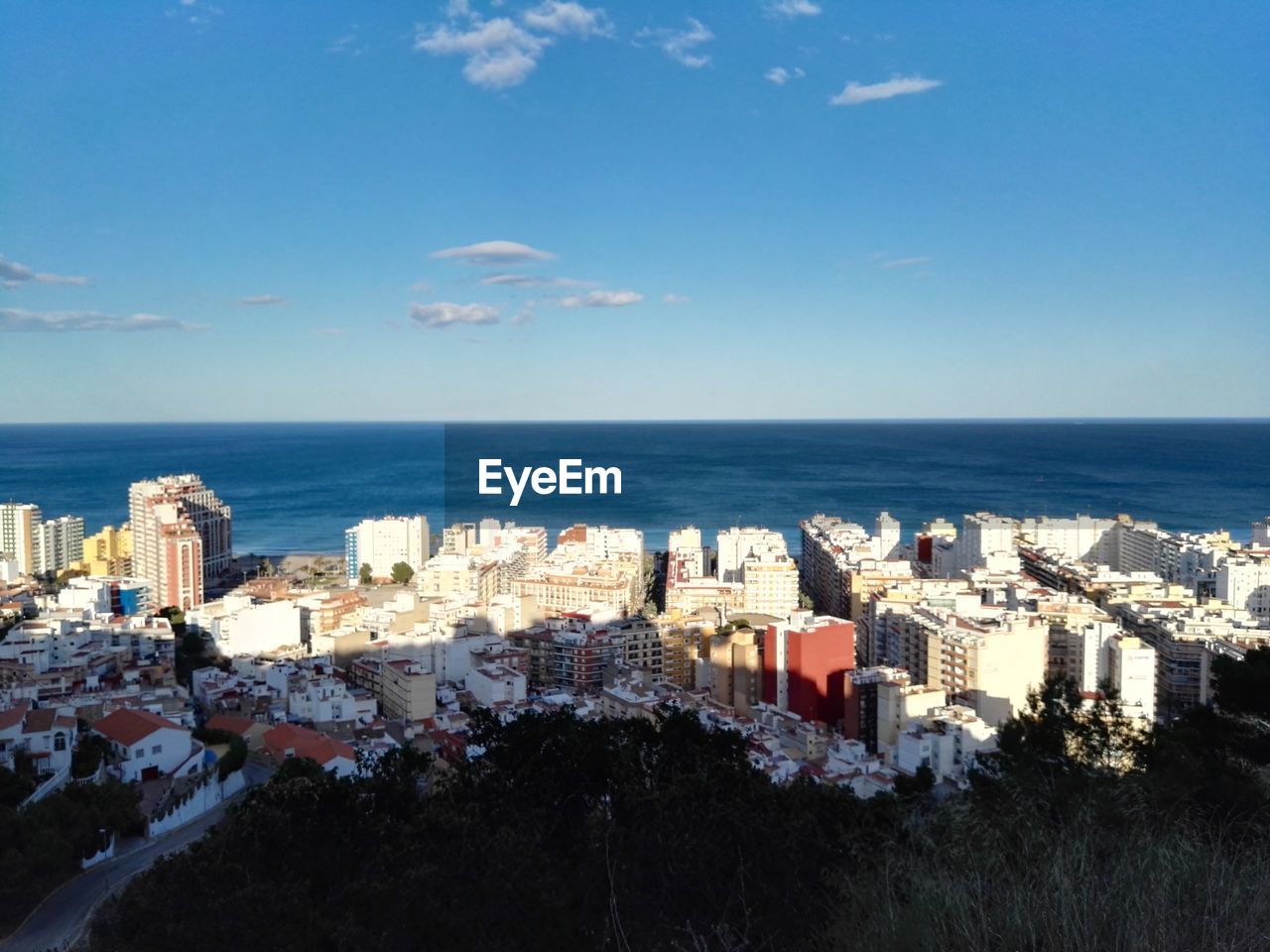 Cityscape by sea against blue sky