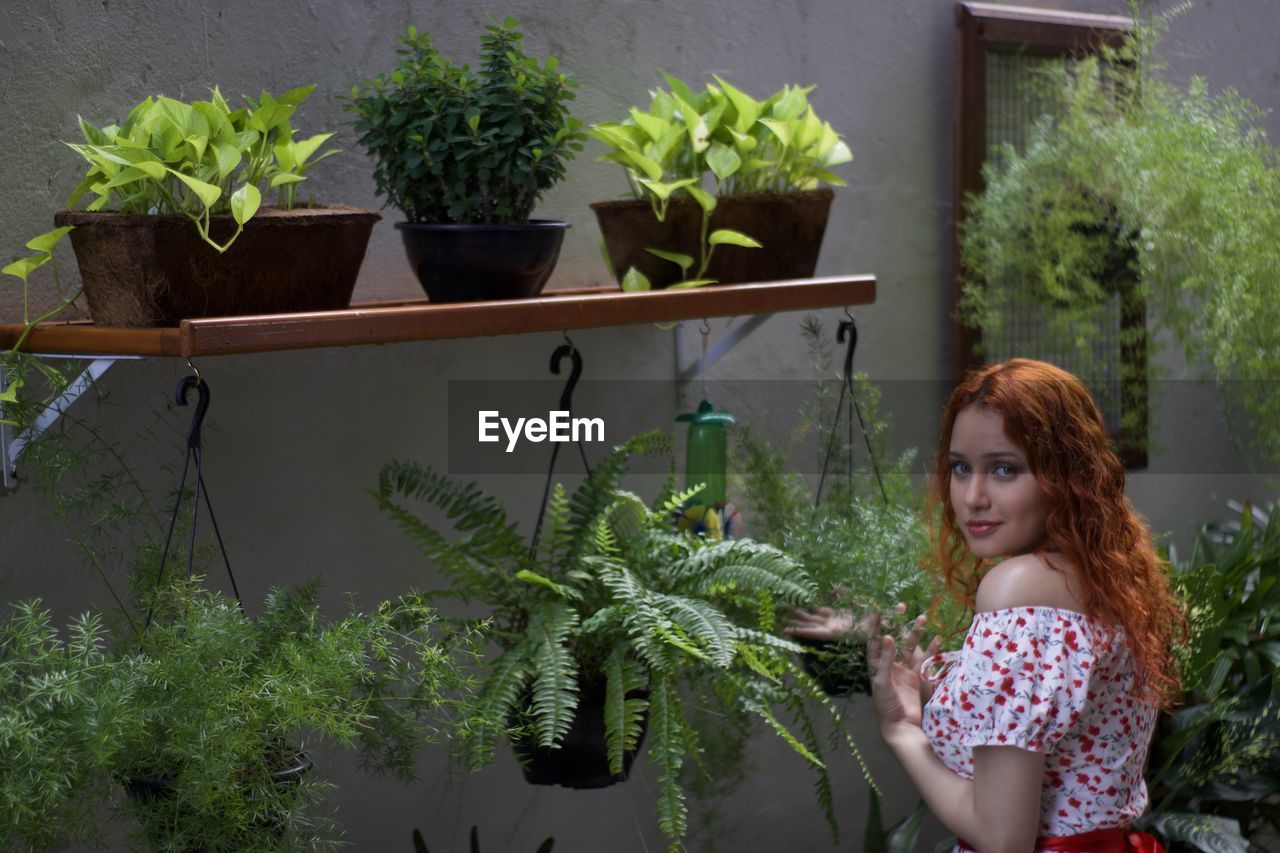 Portrait of young woman against potted plants