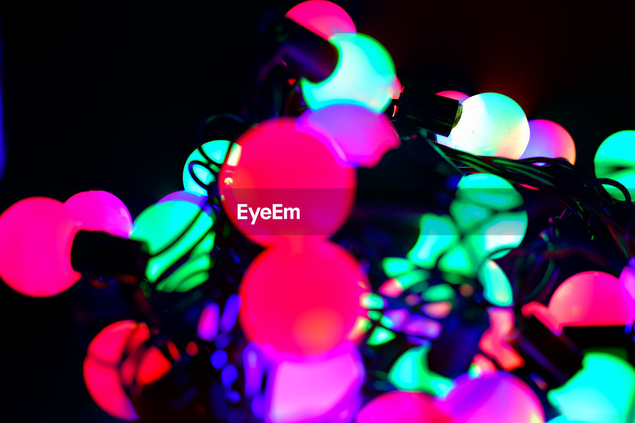 CLOSE-UP OF MULTI COLORED BALLOONS AGAINST ILLUMINATED LIGHTS