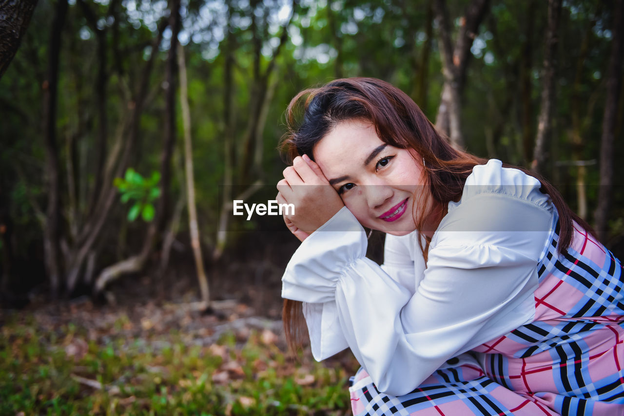 PORTRAIT OF A SMILING YOUNG WOMAN OUTDOORS