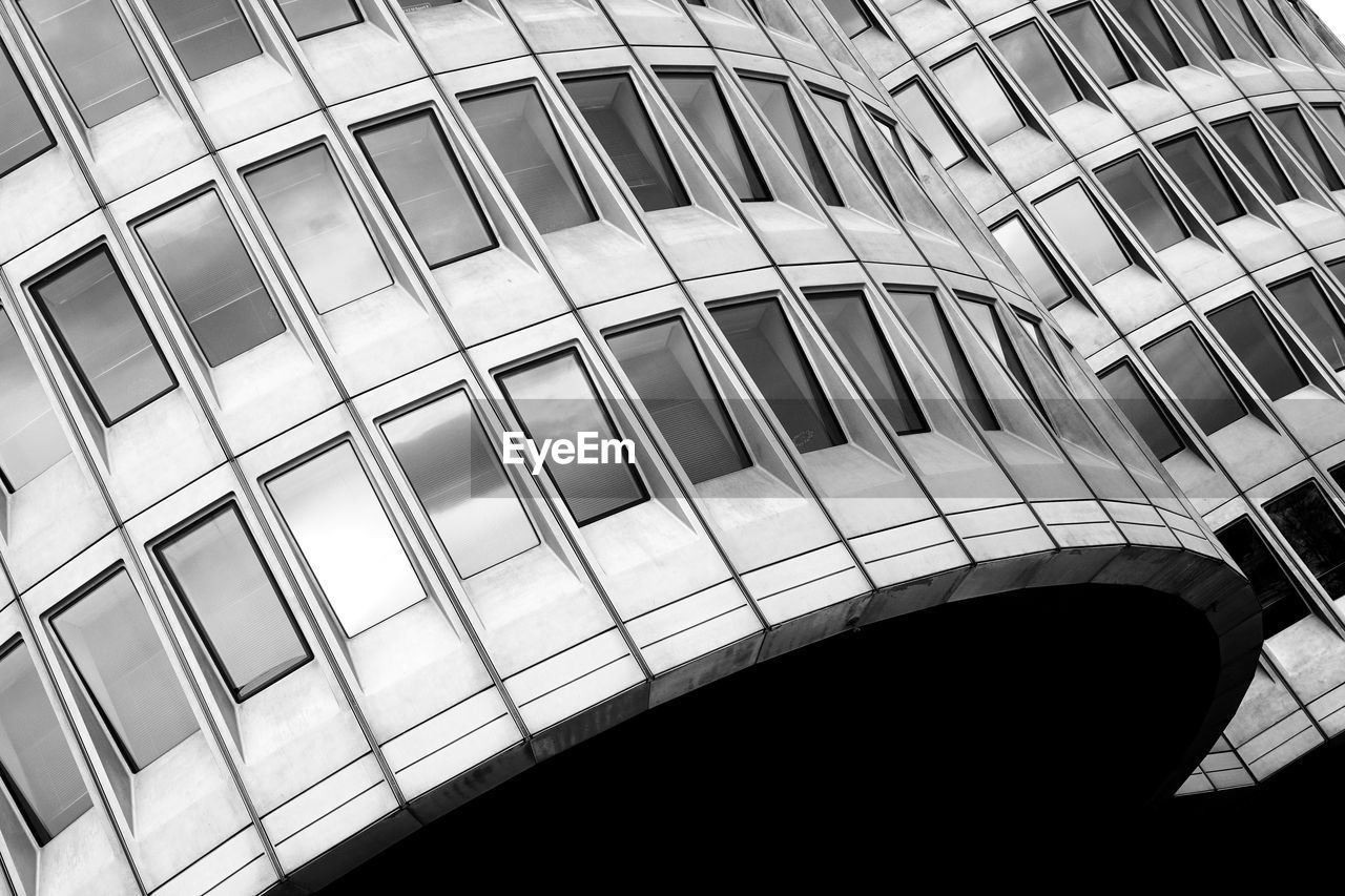 LOW ANGLE VIEW OF MODERN GLASS BUILDING AGAINST SKY