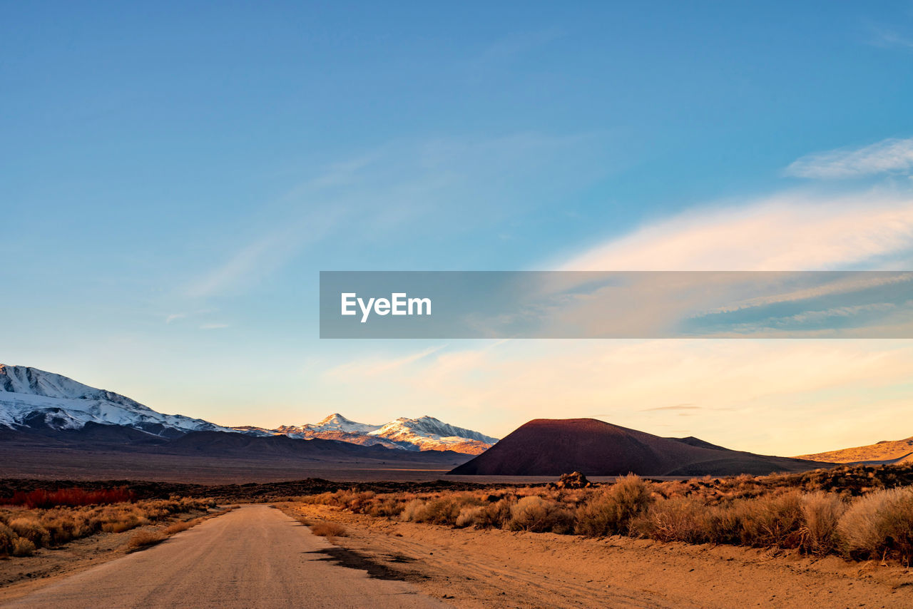 Road leading towards desert against sky