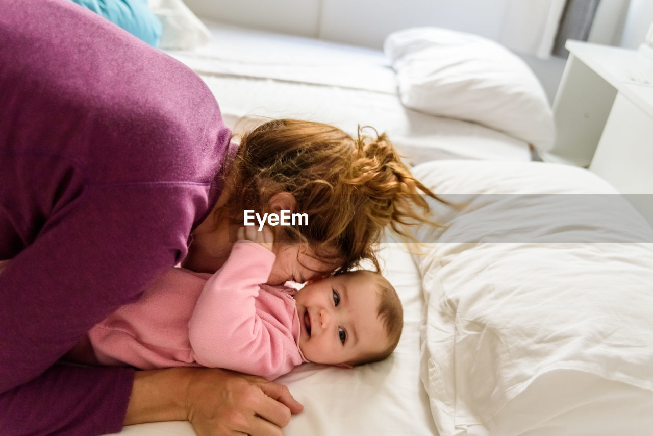 Mother and baby lying on bed at home