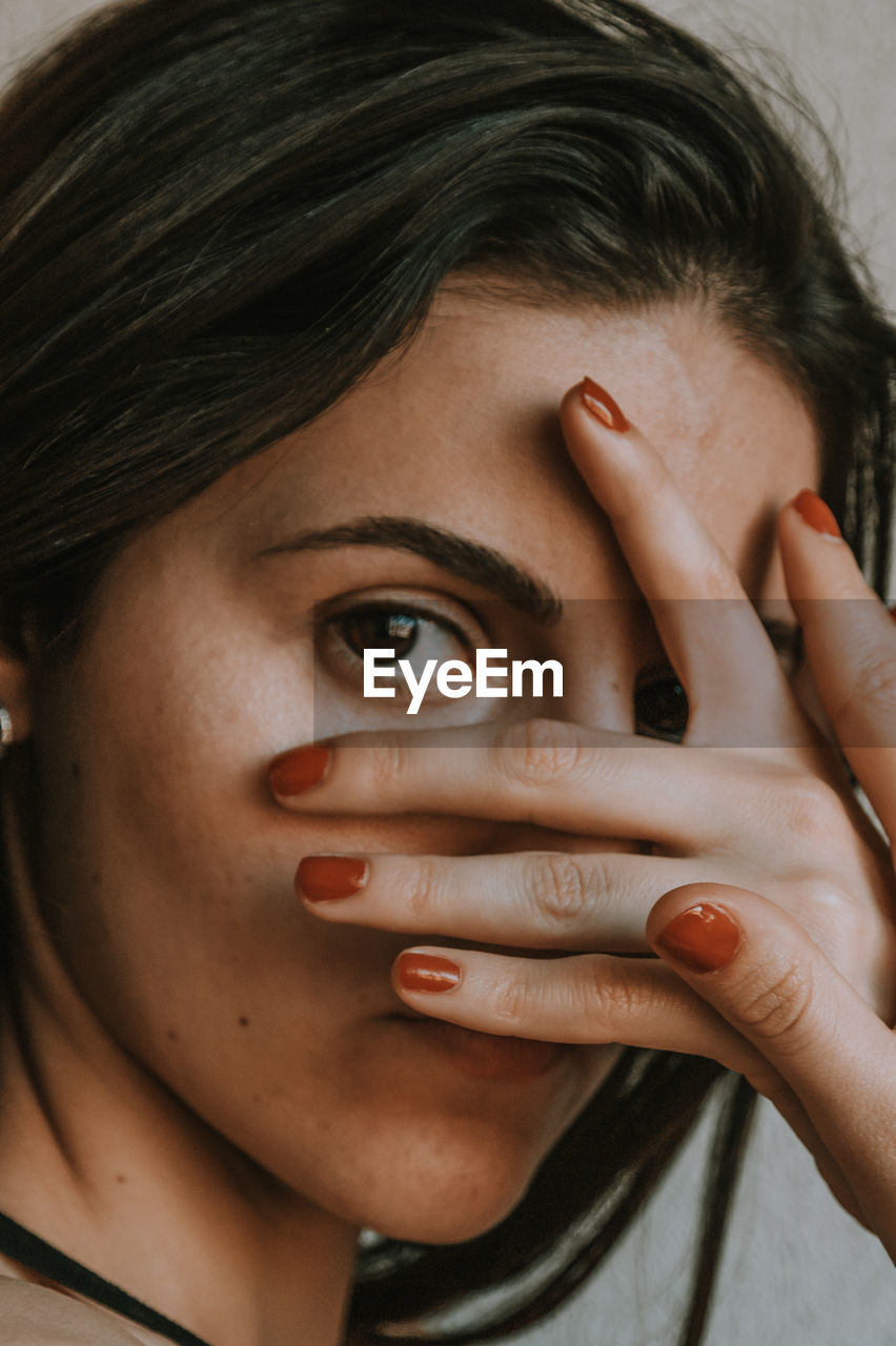 Close-up portrait of woman covering face with hand