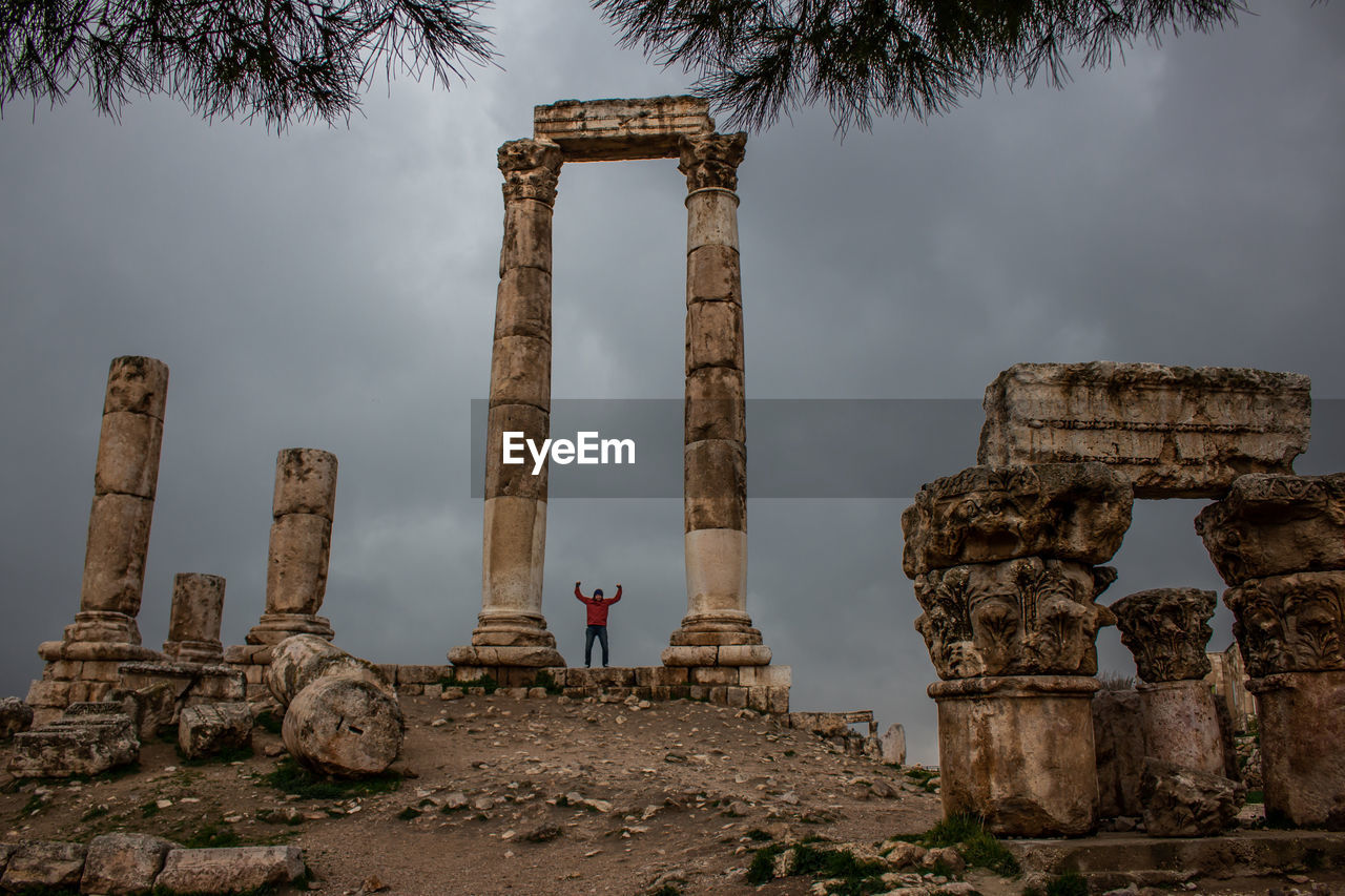 Man with arms raised standing at temple of hercules