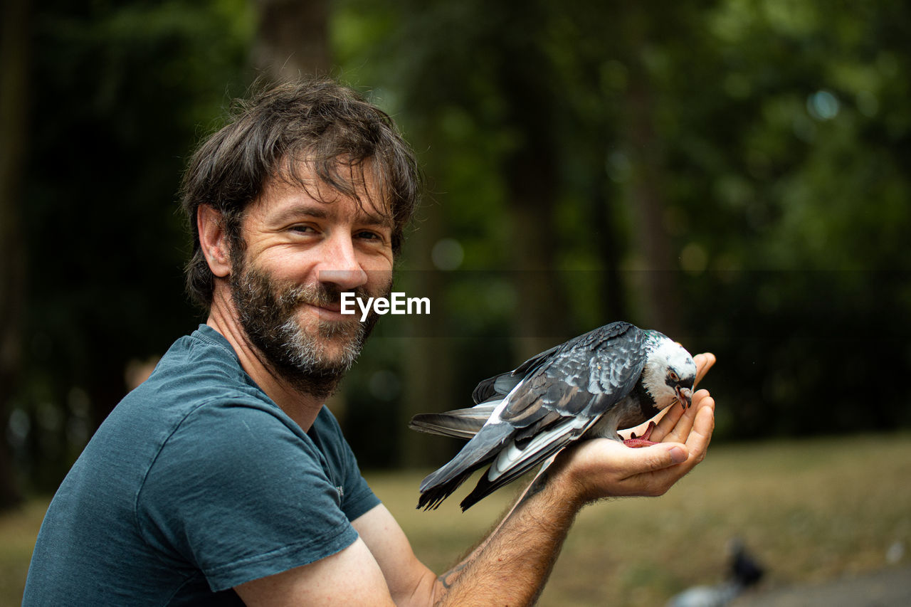 animal, one person, adult, animal themes, men, one animal, smiling, portrait, happiness, emotion, beard, bird, animal wildlife, facial hair, nature, holding, casual clothing, cheerful, wildlife, looking at camera, pet, day, outdoors, focus on foreground, positive emotion, headshot, lifestyles, domestic animals, fishing, person