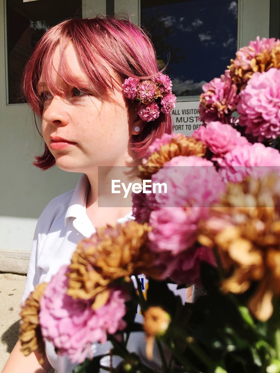 Close-up of beautiful young woman with bouquet during sunny day