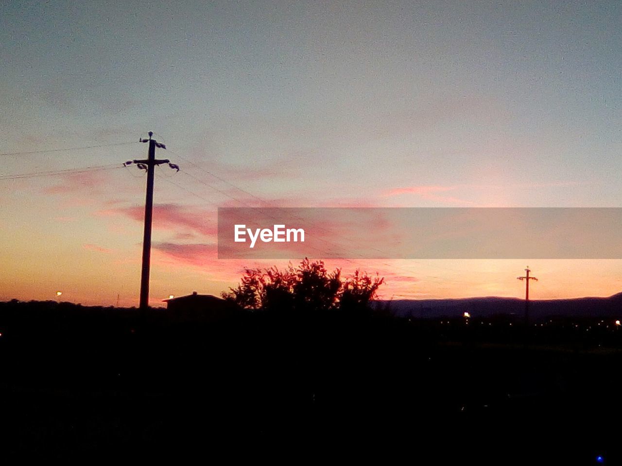 SILHOUETTE OF ELECTRICITY PYLON AGAINST SKY DURING SUNSET