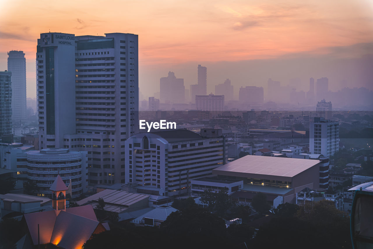 HIGH ANGLE VIEW OF BUILDINGS AGAINST SKY AT SUNSET