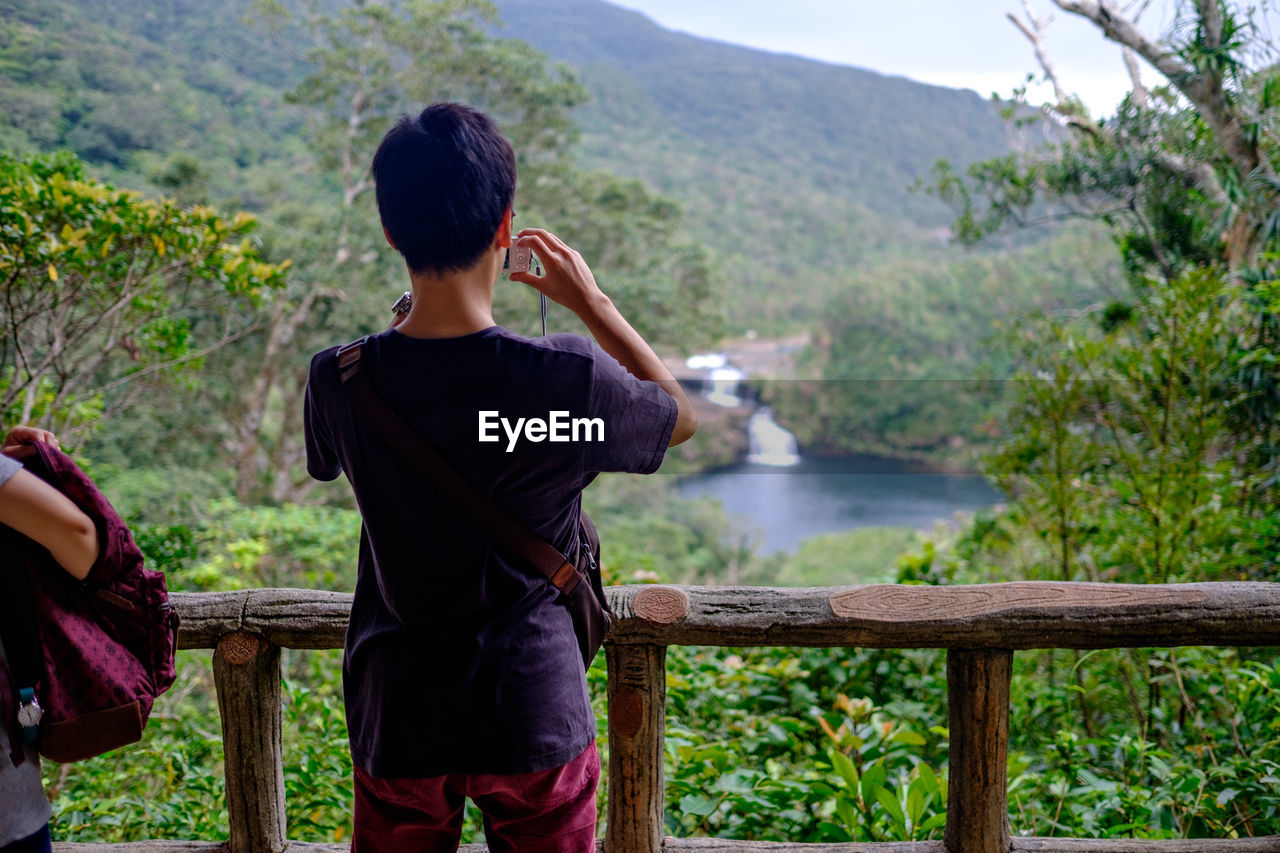 Rear view of man photographing mountains