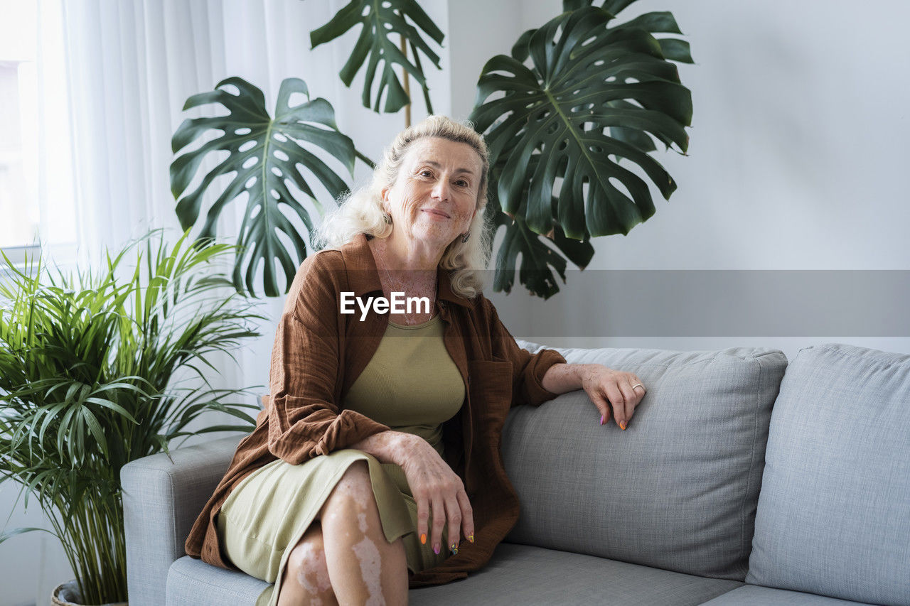 Smiling senior woman sitting on sofa at home