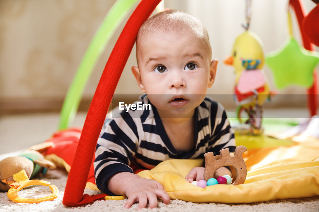 portrait of cute baby boy playing with toys at home