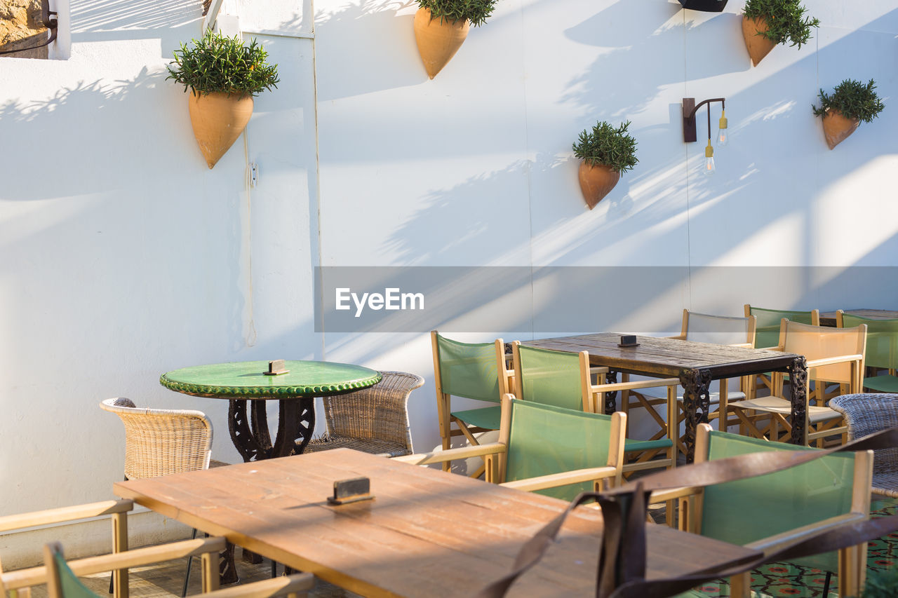 EMPTY CHAIRS AND TABLES IN CAFE AGAINST WALL