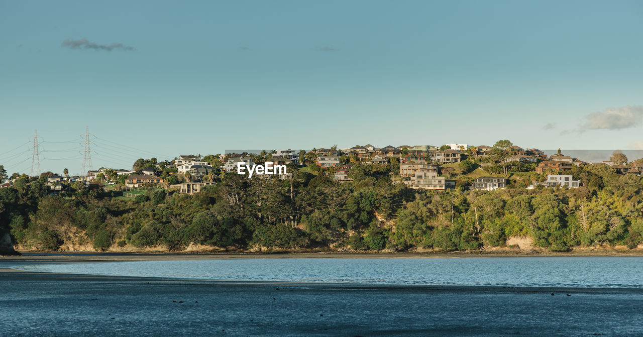 Scenic view of sea by townscape against sky