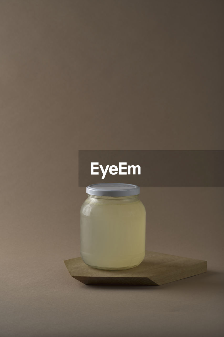 Jar of asparagus stock on a wooden cutting board with brown background