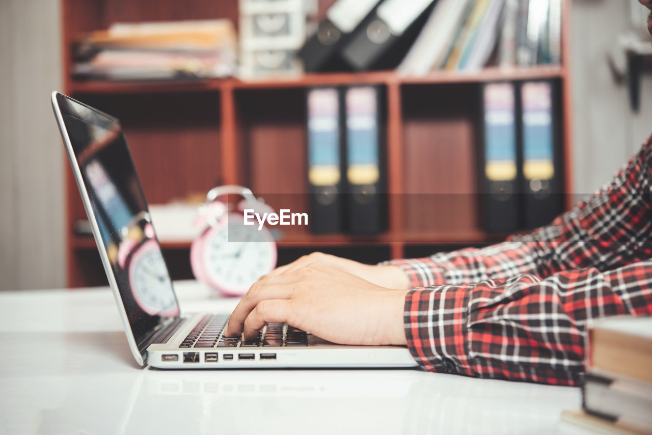 MAN USING LAPTOP ON TABLE AT HOME