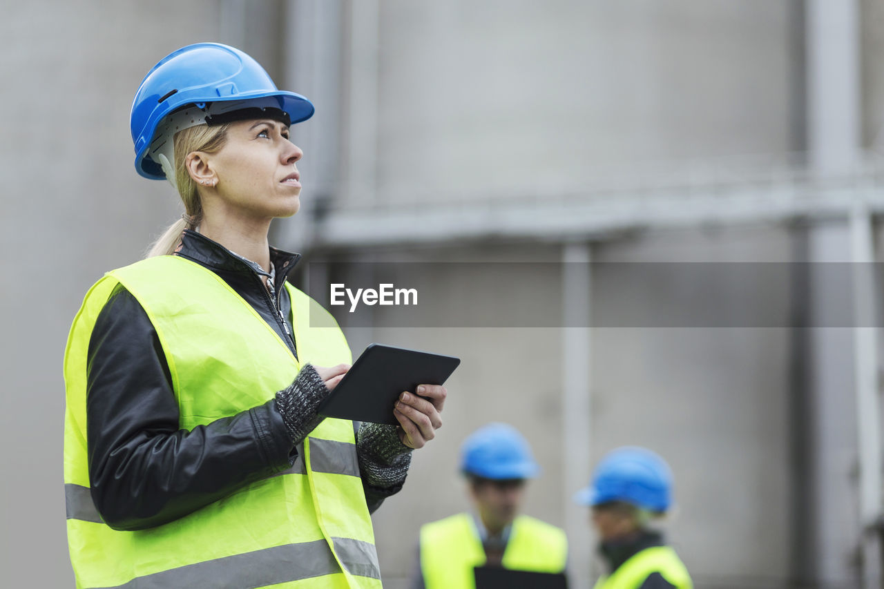 Female worker using digital tablet while looking away at factory