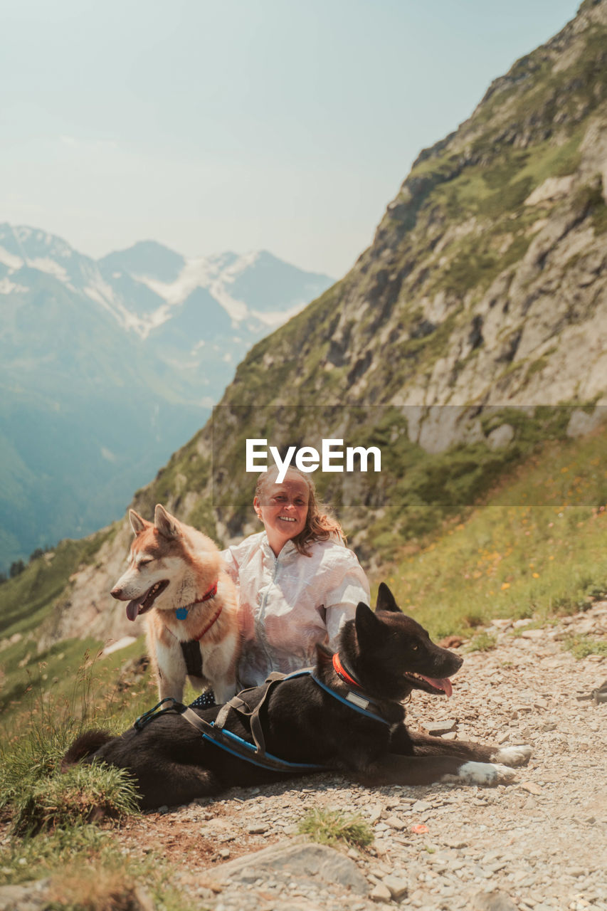 Woman sitting on mountain against sky