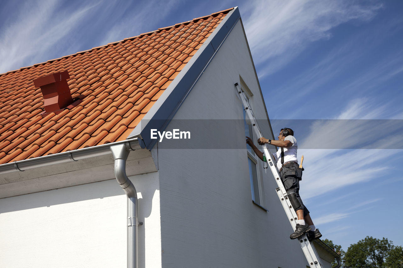 Man on ladder doing house repairs