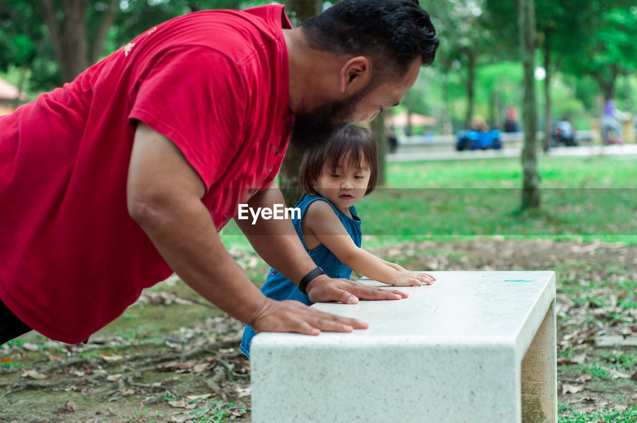 Rear view of father and toddler daughter outdoors.