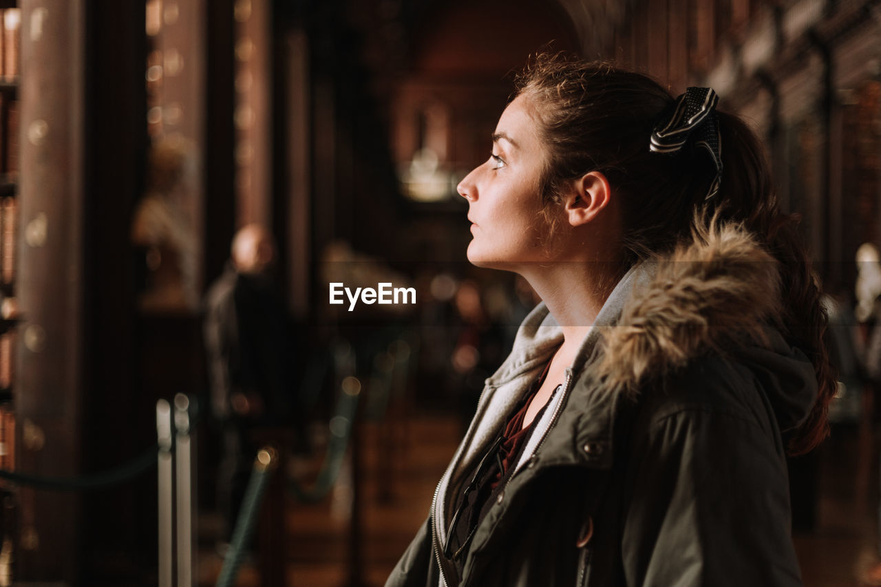 Contemplating young woman looking away while standing in city at night