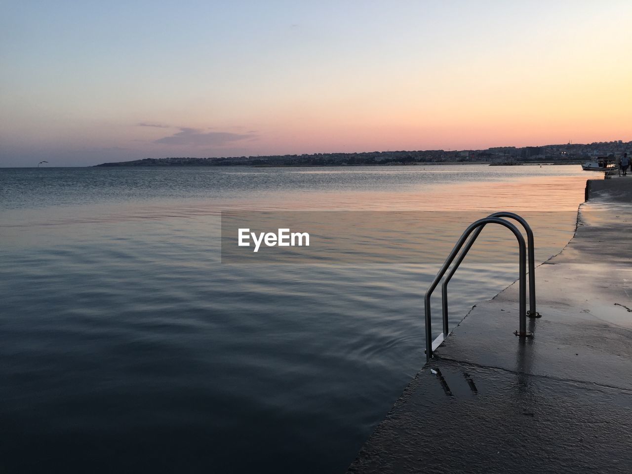 Railing on pier by sea against sky during sunset