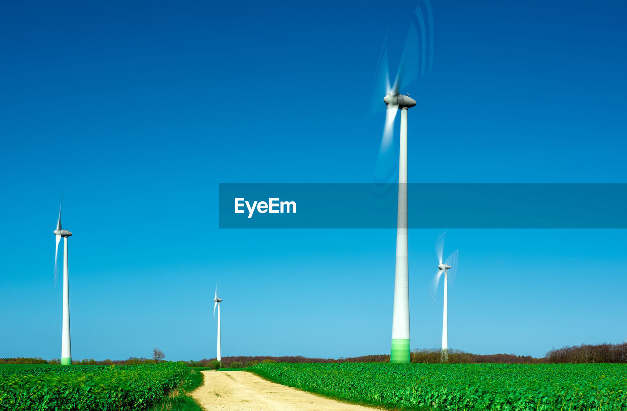 Low angle view of windmill against clear blue sky