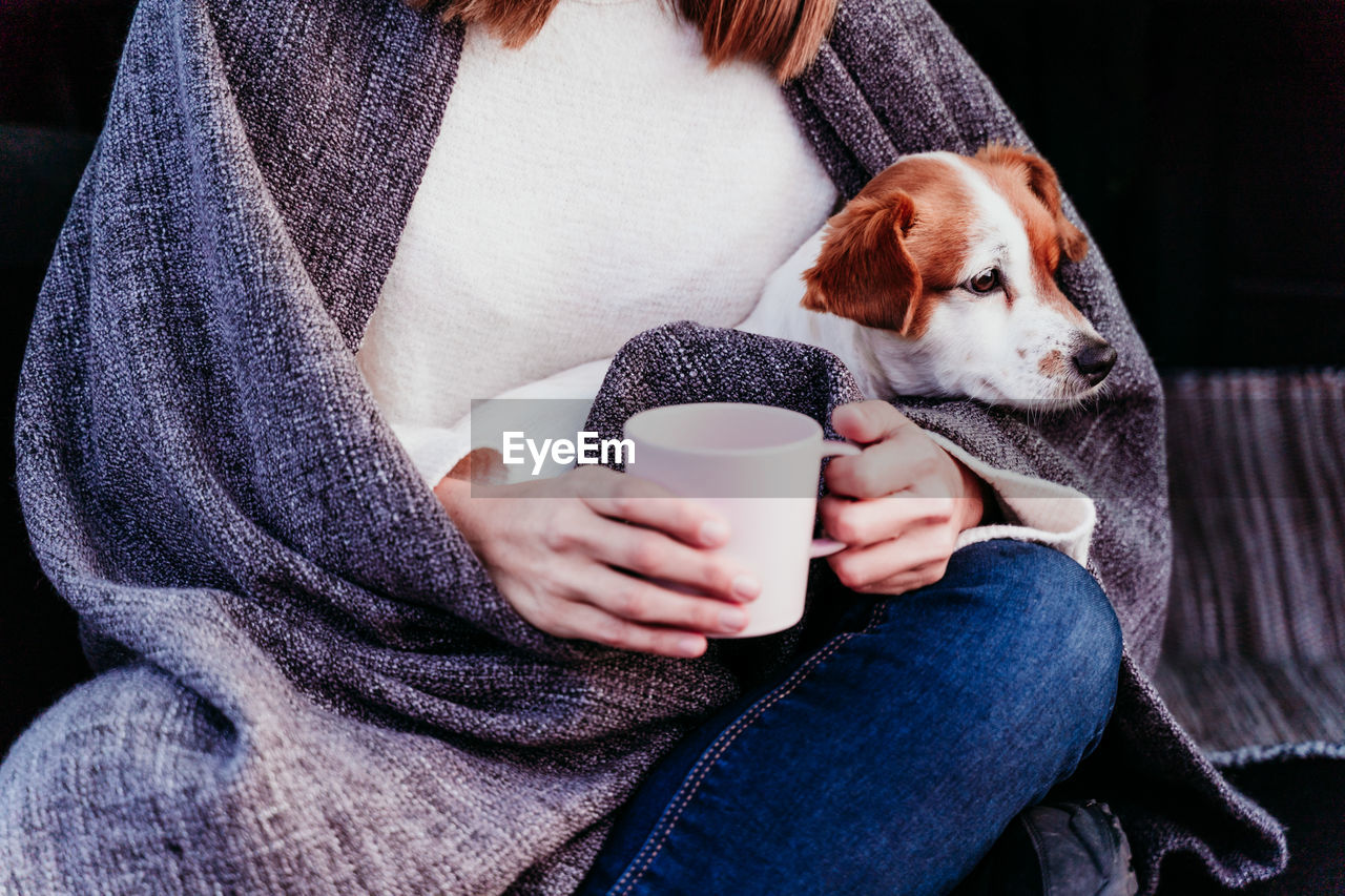 MIDSECTION OF MAN WITH DOG IN CUP