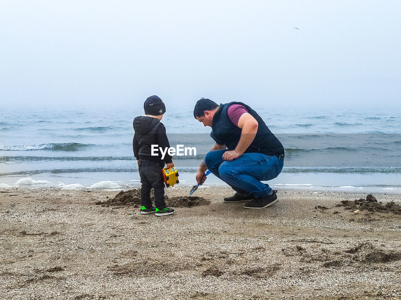 Father and son digging at sea shore