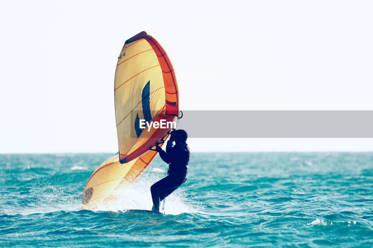 man kayaking in sea against clear sky