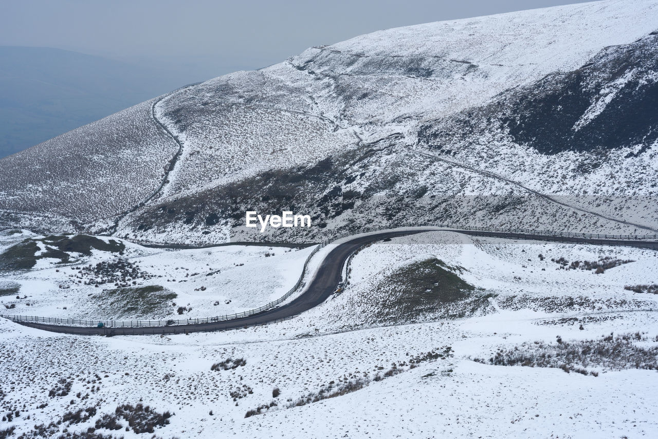 Snow covered road by mountain against sky