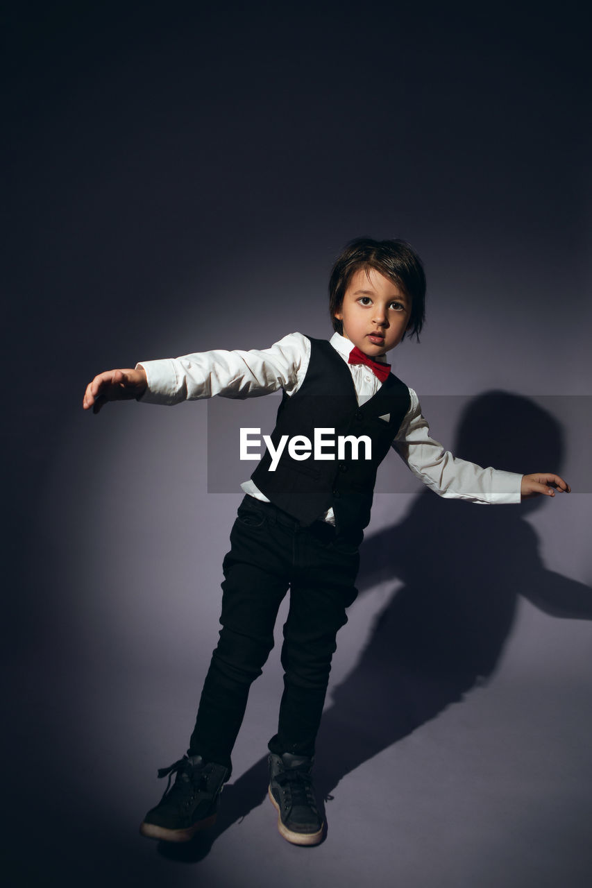 Stylish boy child of four years in the studio on the background in a vest and a red bow tie