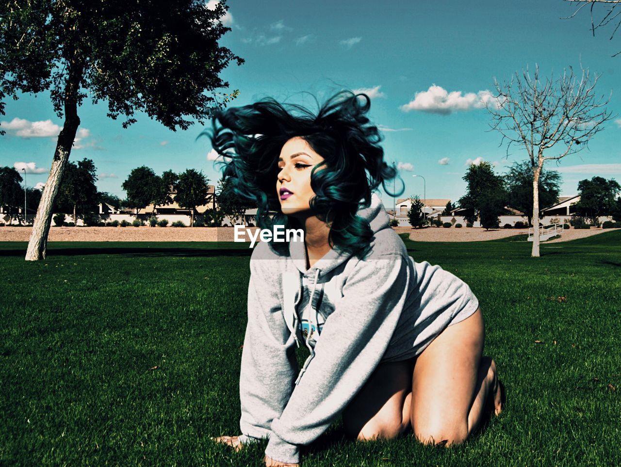 WOMAN STANDING ON GRASSY FIELD IN PARK