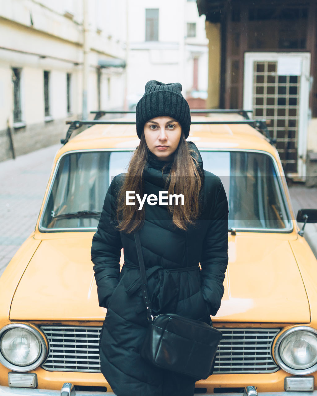 Portrait of beautiful young woman leaning on car parked at street