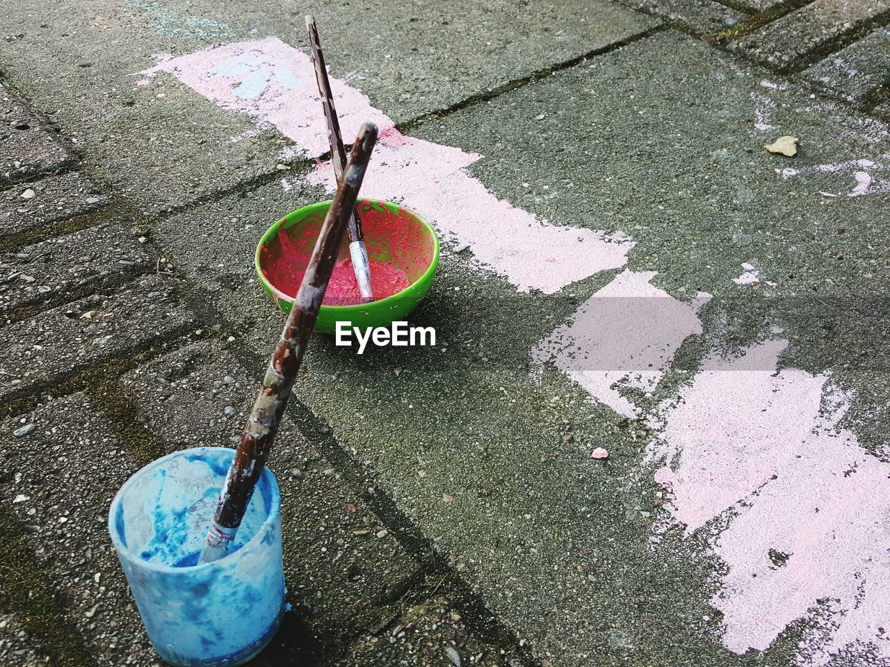 High angle view of powdered paints and brushes in bowls on street